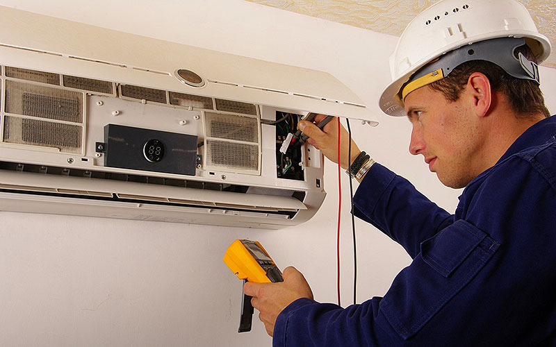 Imagen de un técnico haciendo mantenimiento a un aire acondicionado.